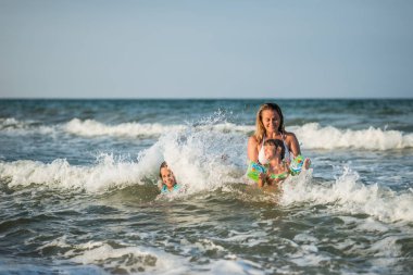 Cheerful young mother swims in the sea clipart