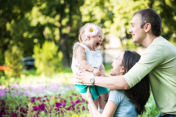 Föräldrar som går, leker och kysser sin lilla dotter i parken — Stockfoto