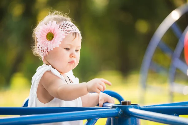 Kleines Mädchen mit Blume im Haar beim Karussell im Freien — Stockfoto