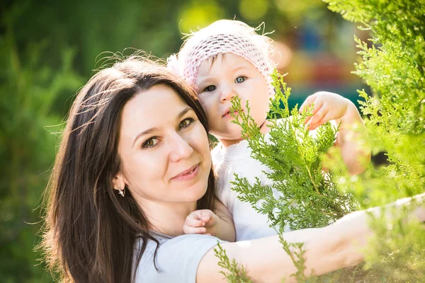 Jovem mãe segurando sua pequena filha em mãos ao ar livre — Fotografia de Stock