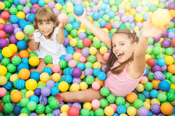 Niños alegres en la sala de juegos con bolas de plástico —  Fotos de Stock