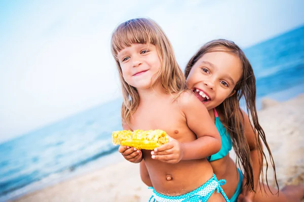 Duas crianças se divertindo na praia e comendo milho — Fotografia de Stock
