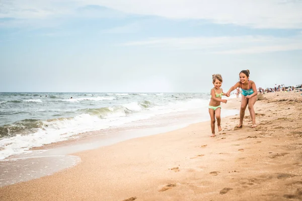 Deux petites filles positives courent le long de la plage de sable — Photo