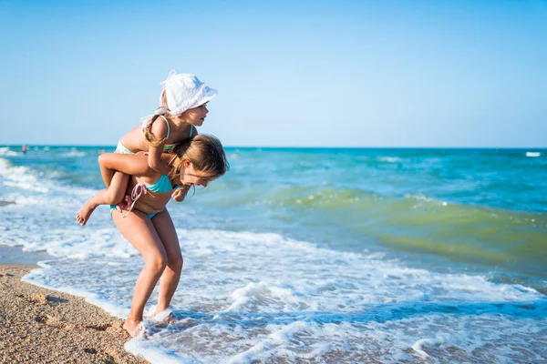 Souriante petite fille porte sa petite sœur charmante — Photo