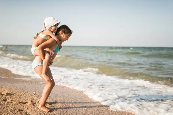 Sonriente niña lleva a su pequeña hermana encantadora — Foto de Stock