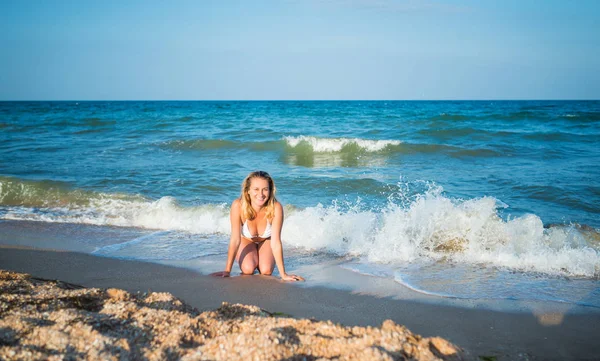 Güzel, mutlu genç bir kadın ıslak kumda yatıyor. — Stok fotoğraf
