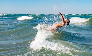Gürültülü denizde sıçrayan küçük neşeli aktif kız.