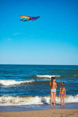 İki neşeli kız kardeş uçurtmayla oynuyorlar.