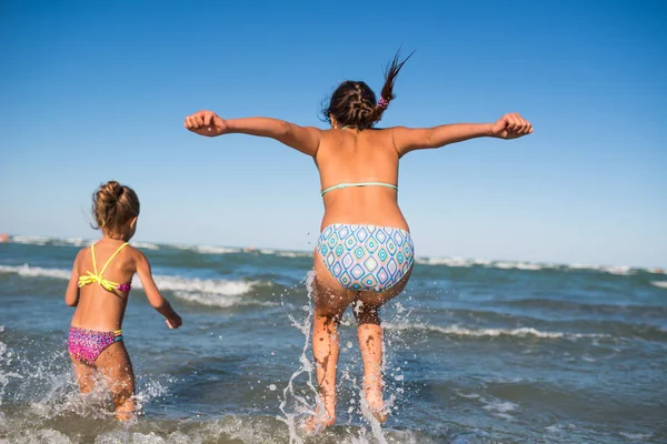 Deux petites filles drôles sautent dans les vagues bruyantes de la mer — Photo