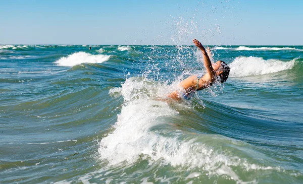 Gürültülü denizde sıçrayan küçük neşeli aktif kız.
