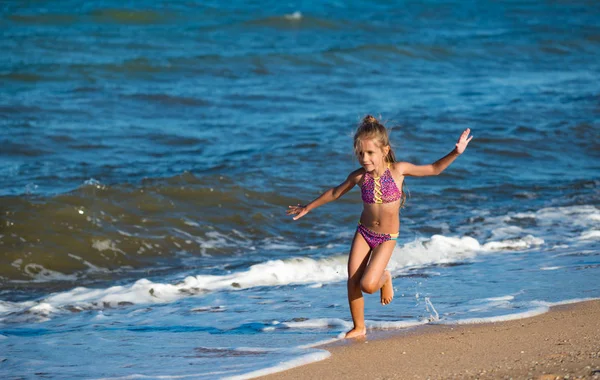 Ragazzina felice corre lungo la riva sabbiosa — Foto Stock