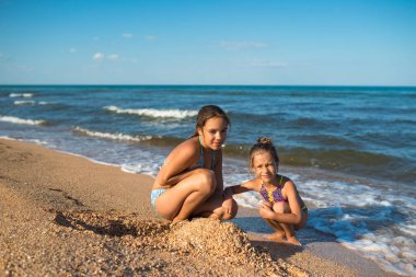 İki tatlı kız kardeş kumsalda oynuyor.