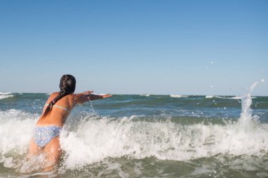 Gürültülü denizde sıçrayan küçük neşeli aktif kız.