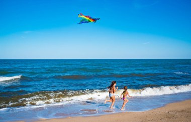 İki küçük mutlu kız uçurtmayla koşuyor