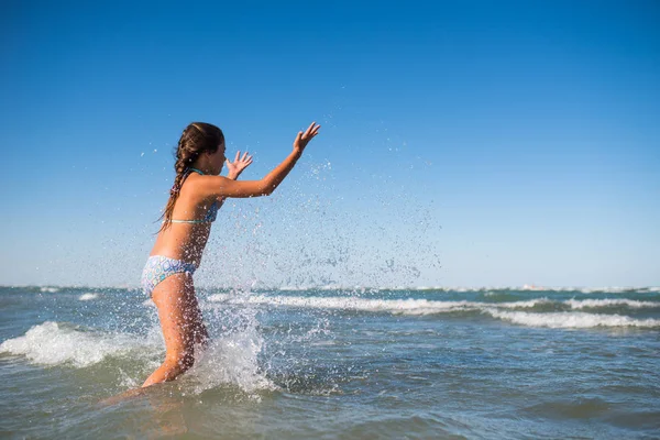 Pouco engraçado menina ativa espirrando no mar barulhento — Fotografia de Stock