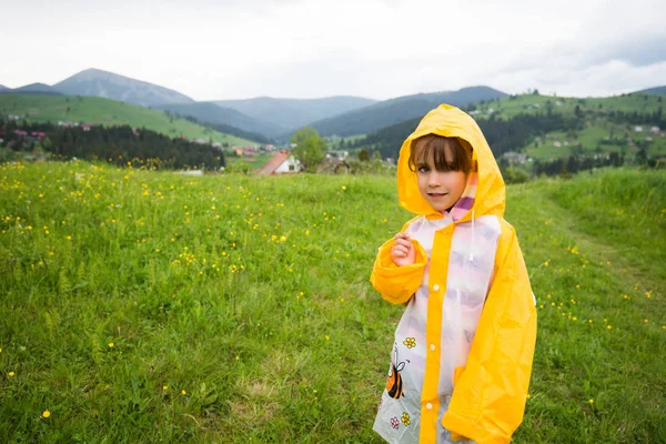 Chica en una chaqueta amarilla camina por un campo —  Fotos de Stock