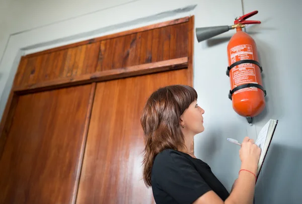 Jonge vrouw brandweer inspecteur schrijft — Stockfoto