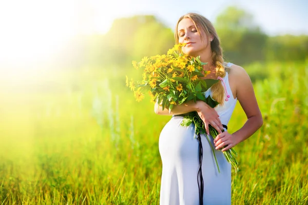 Zwanger meisje met boeket bloemen in handen — Stockfoto