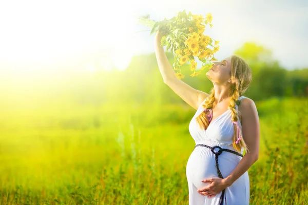 Pregnant girl holding bouquet of flowers in hands — Stock Photo, Image