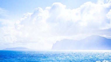 Sandy beach with mountains and cloudy sky