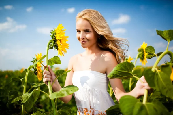 Meisje kijkt naar zonnebloem en glimlacht — Stockfoto