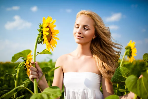 Girl looking at sunflower and smiling — Stock Photo, Image