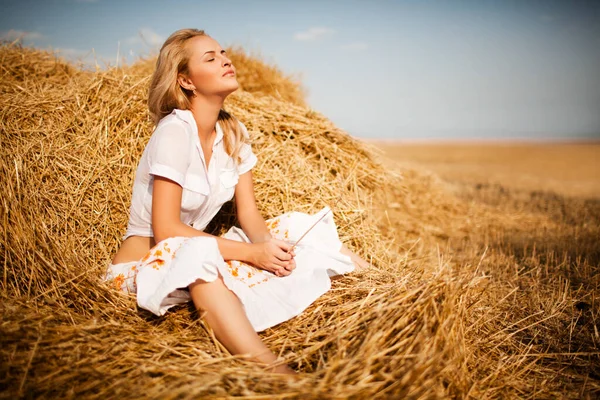 Girl with blond hair lying in hay — Stock Photo, Image