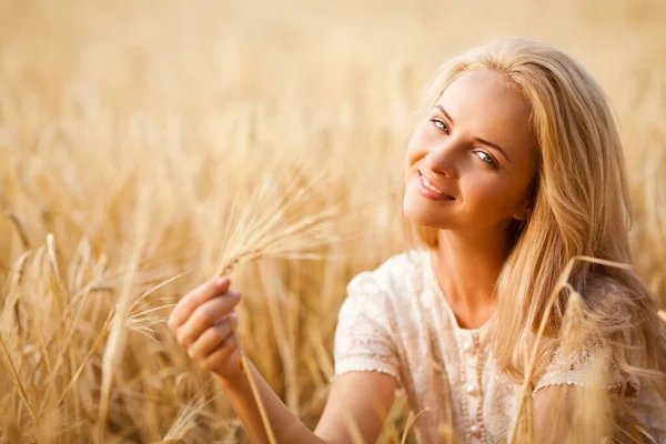 Woman smiling and sitting on wheat field — Stock Photo, Image