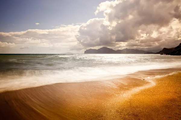 Песчаный пляж с горами и облачным небом — стоковое фото