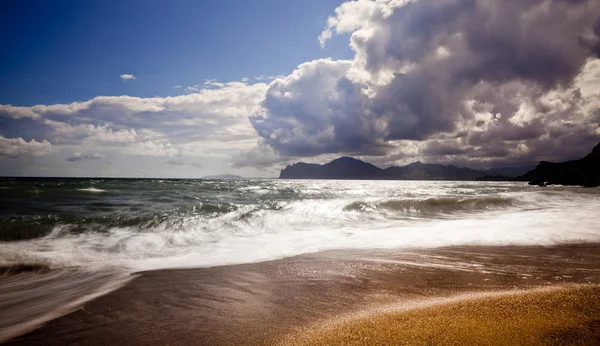 Playa de arena con montañas y cielo nublado — Foto de Stock