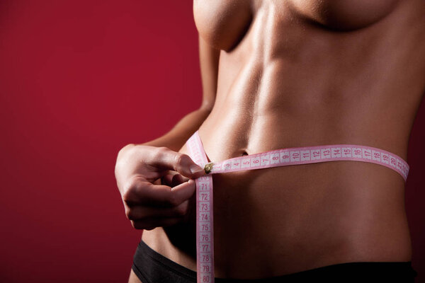 Топлесс девушки в черных трусиках измеряет ее талию
