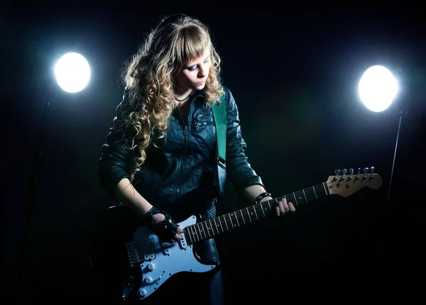 Girl guitarist with spotlights behind her — Stok fotoğraf