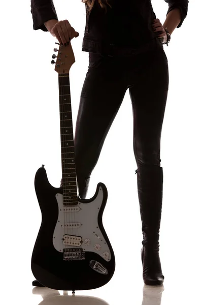 Гітара поруч з жіночими ногами в шкіряних легінсах — стокове фото