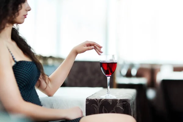 Menina sentada à mesa com um copo de vinho na mão — Fotografia de Stock