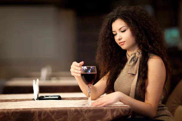 Dívka s kudrnatými vlasy drží skleněné víno v ruce — Stock fotografie