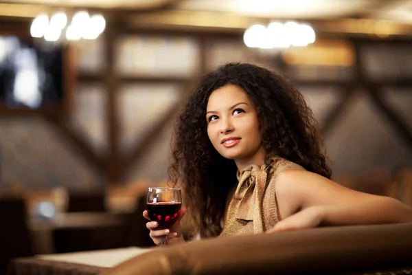 Menina com cabelo encaracolado segurando vinho de vidro na mão — Fotografia de Stock