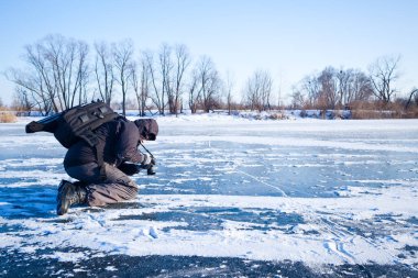 Man taking pictures river covered in ice and snow