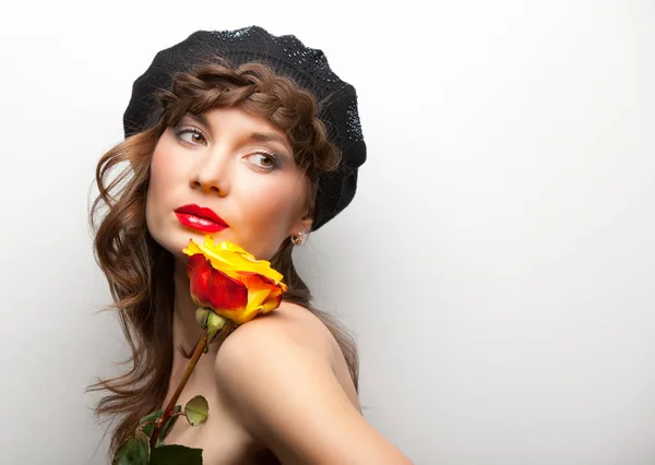 Woman in hat holding rose near her face — ストック写真
