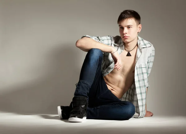 Guy in unbuttoned check shirt lying on his side — ストック写真