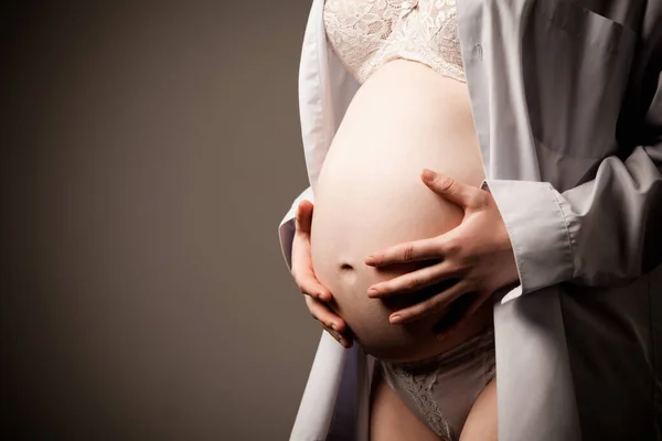 Pregnant woman holding hands on her belly Stock Picture