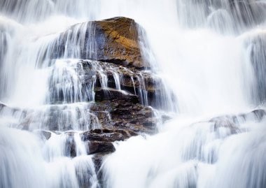 Waterfall pours from cliff to stones