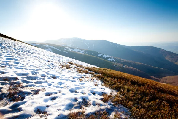 Montanha com neve e grama, tempo ensolarado — Fotografia de Stock