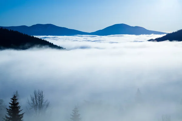 Niebla blanca gruesa entre los picos de montaña —  Fotos de Stock
