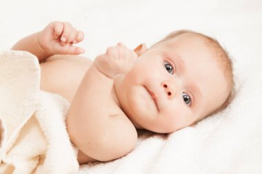 Adorable baby lying on white sheets. clipart