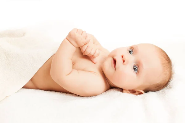 Entzückendes Baby auf weißen Laken liegend. — Stockfoto