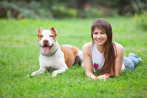 Cheerful lady lying on grass with dog. — Stock Photo, Image