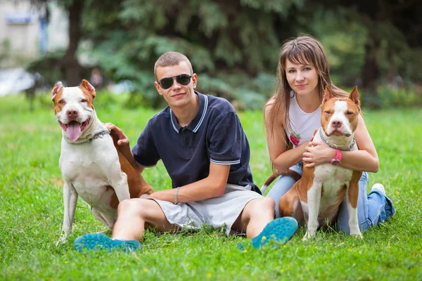 Hermosa pareja sentada en la hierba con perros . —  Fotos de Stock