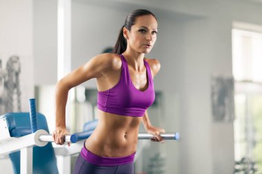 Sportif kadın spor salonunda barfiks çekiyor..