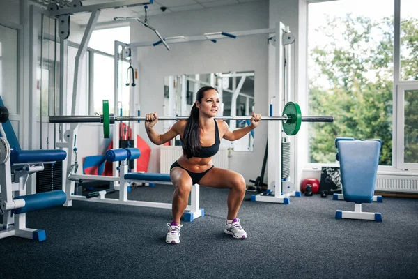 Fitness kvinna gör knäböj med skivstång. — Stockfoto