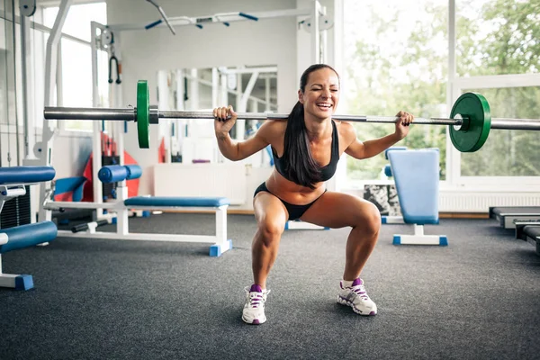 Fitness kvinna gör knäböj med skivstång. — Stockfoto